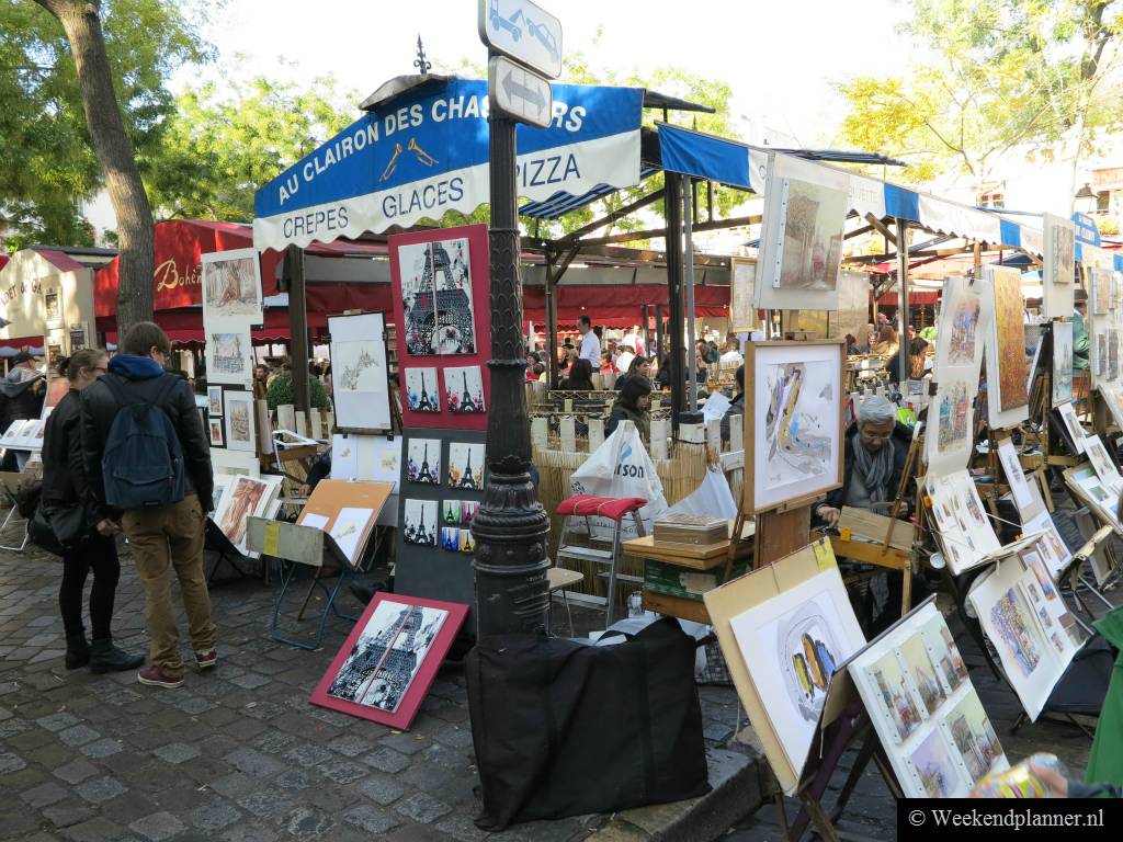Op het midden van het plein liggen de terrasjes van de cafés en de restaurants. De schilders hebben hun koopwaar uitgestald langs de terrasjes.